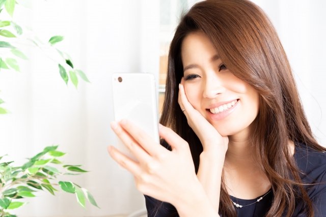 dカードゴールドとスマホを見て笑っている女性
